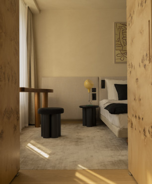 Klasyczna sypialnia z tapicerowanym łóżkiem kontynentalnym oraz czarnym stolikiem