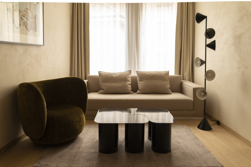 Klasyczny salon o małym metrażu z fotelem, sofą, stolikiem kawowym oraz lampą stojącą