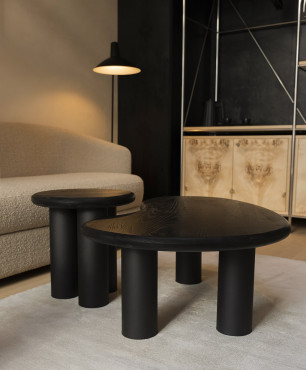 Salon z jasną tapicerowaną sofą oraz czarnymi stolikami kawowymi