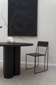 Czarny okrągły stół, czarne krzesło oraz czarny obraz w salonie