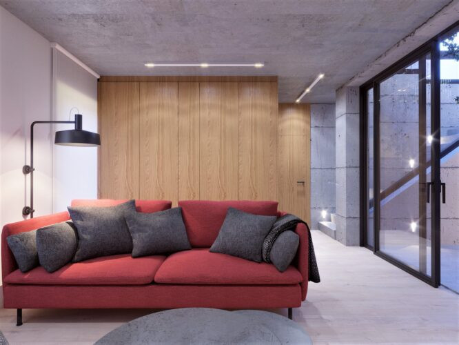 Salon z czerwoną sofą i szarymi poduszkami